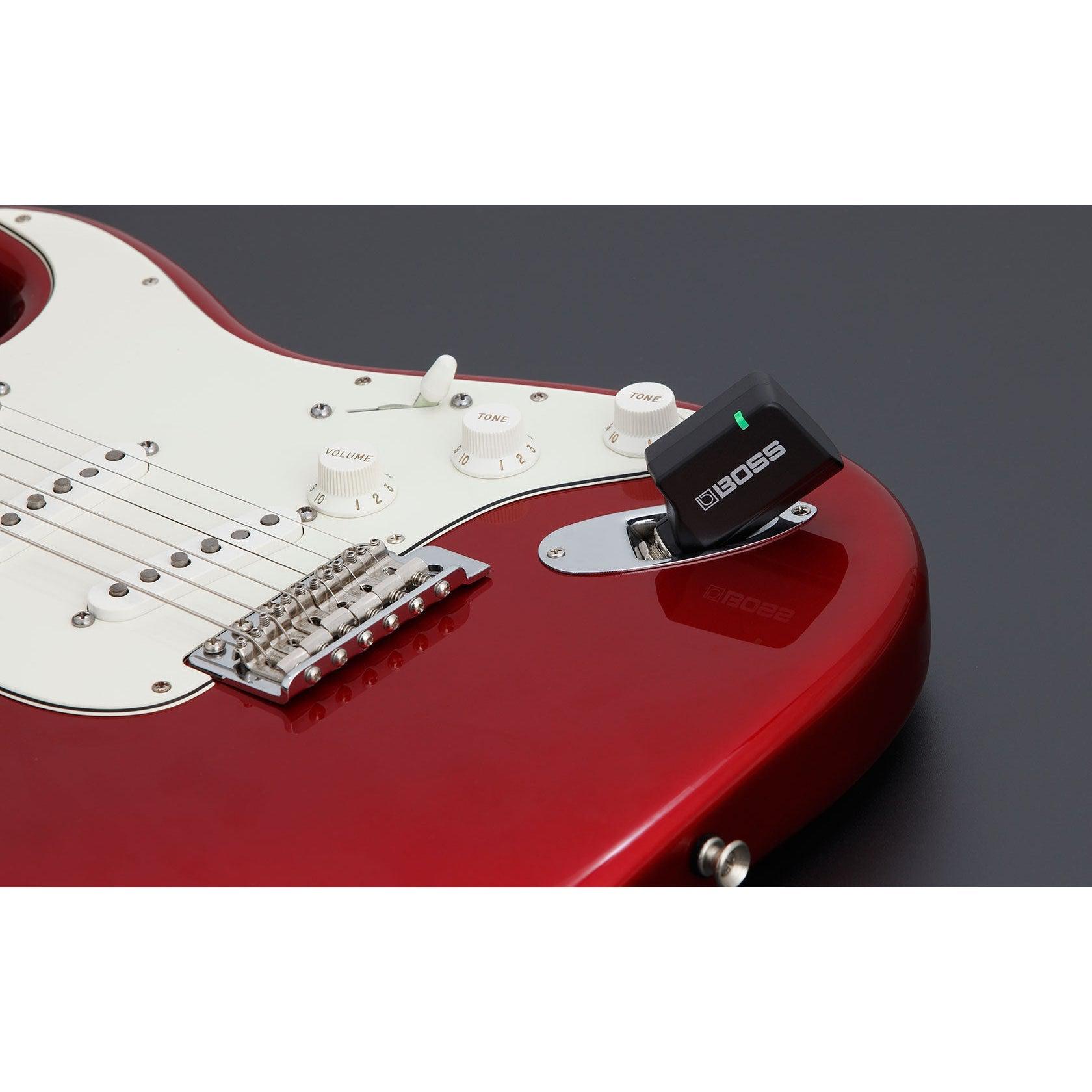 Rød elektrisk guitar med trådløs Boss Katana Air sender tilsluttet tonekontrolpanelet.
