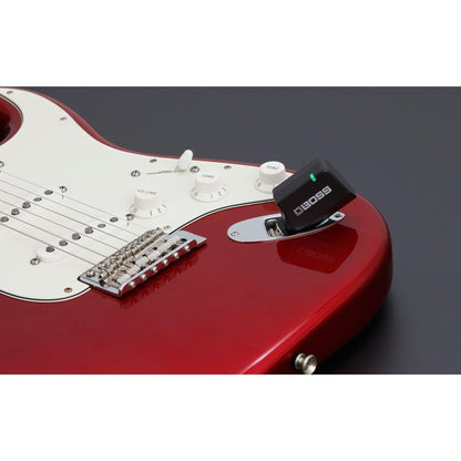 Rød elektrisk guitar med trådløs Boss Katana Air sender tilsluttet tonekontrolpanelet.