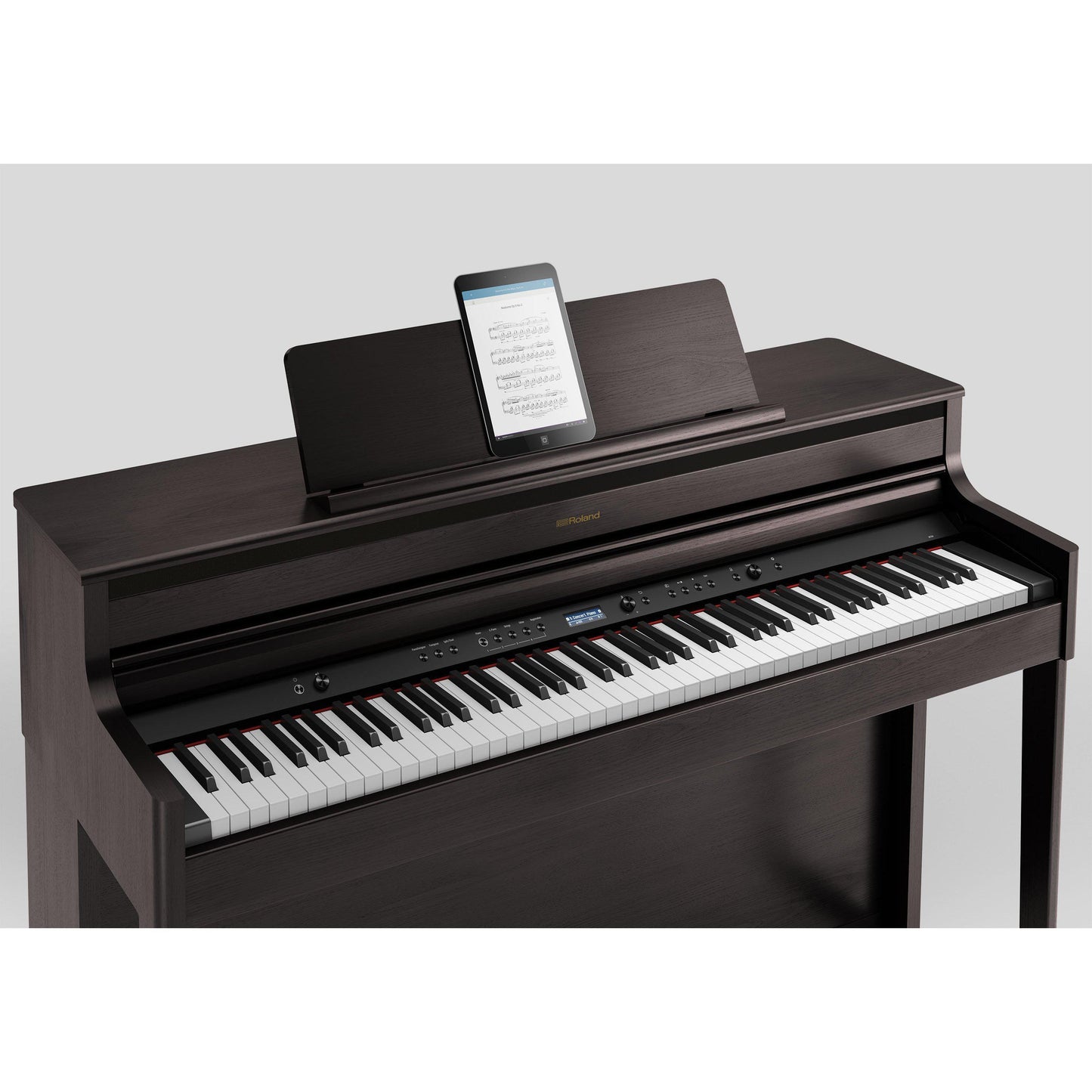 Digitalt piano med mørkt træfinish og tablet til noder på topfladen.