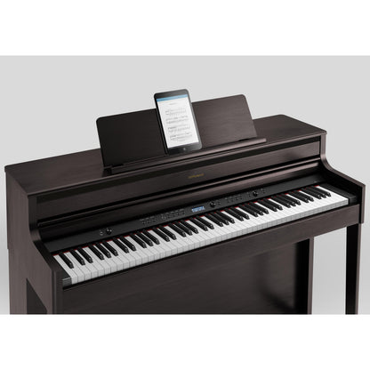 Digitalt piano med mørkt træfinish og tablet til noder på topfladen.
